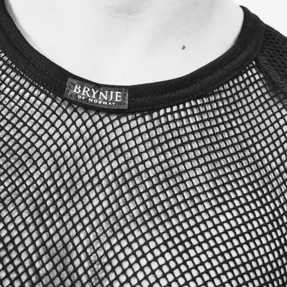 Close-up of a black mesh shirt with 'Brynje' brand label on a human.