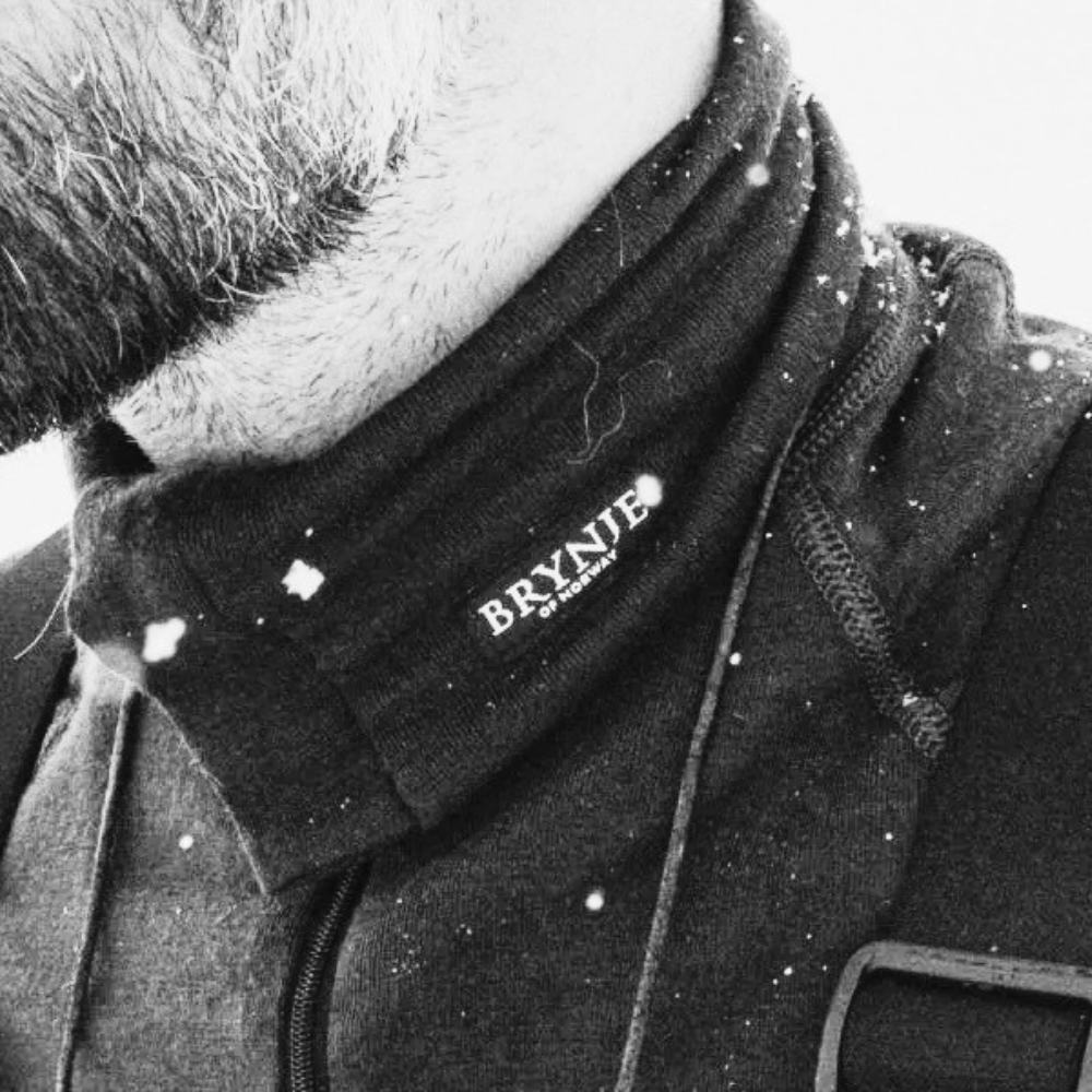 Close-up of a person wearing a black shirt with 'Bryne' branding, in a snowy setting.
